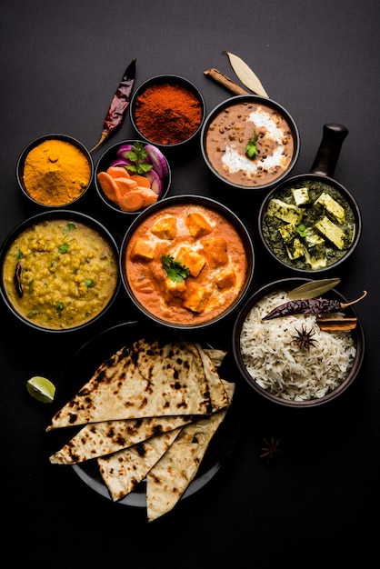 Фото Индийский обед или ужин. основное блюдо в группе включает панир, масло масала, дал махани, палак панир, роти, рис и т. д., выборочный фокус