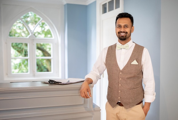 Indian male receptionist wearing uniform standing at counter in hotel