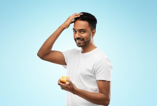 Photo indian man applying hair wax or styling gel