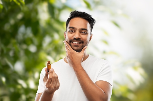 indian man applying natural grooming oil to beard