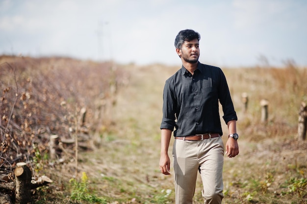 Indian man at black shirt and beige pants posed at field