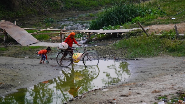 인도인 한 남자가 더러운 물을 가로질러 자전거를 견디지 못한다 (시완 비하르, 인도, 2024년 2월 28일)