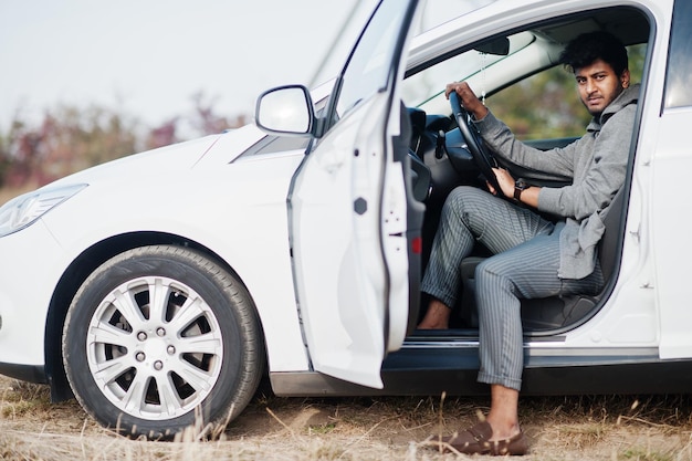 白い車でポーズをとったカジュアルな服装でインド人