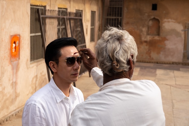 Indian man drawing a dot on tourist forehead on vacation india culture.