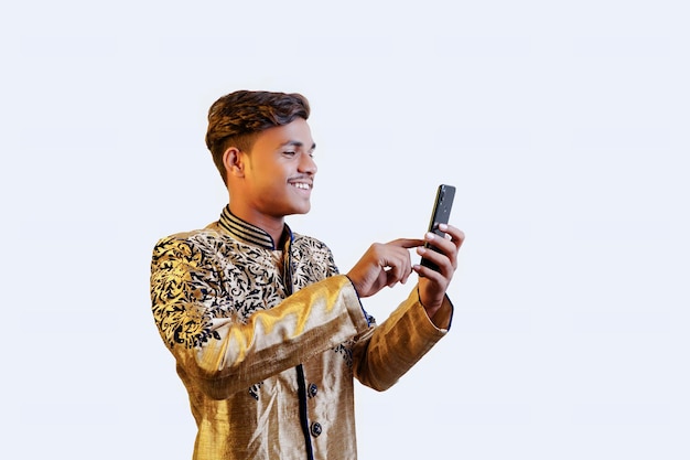 Indian man in ethnic wear showing mobile screen an isolated\
background