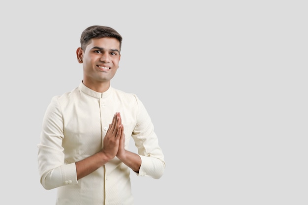 Indian man in ethnic wear and  showing a welcome gestures isolated on white