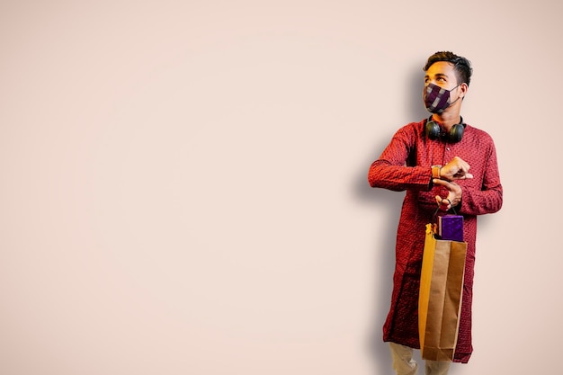 Indian man in ethnic wear with shopping bags isolated over\
yellow background