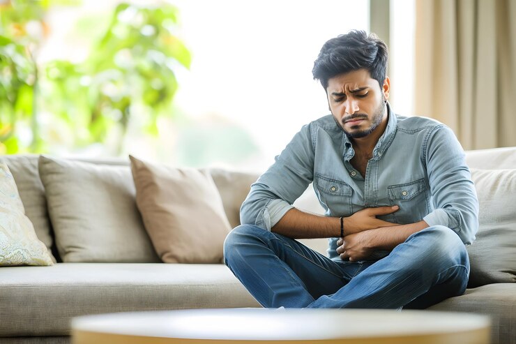 ソファの上で胃の不快感を経験するインド人男性