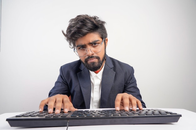 Indian man in glasses working at the computer his hands hover\
over the keyboard while typing isolated on white background front\
view