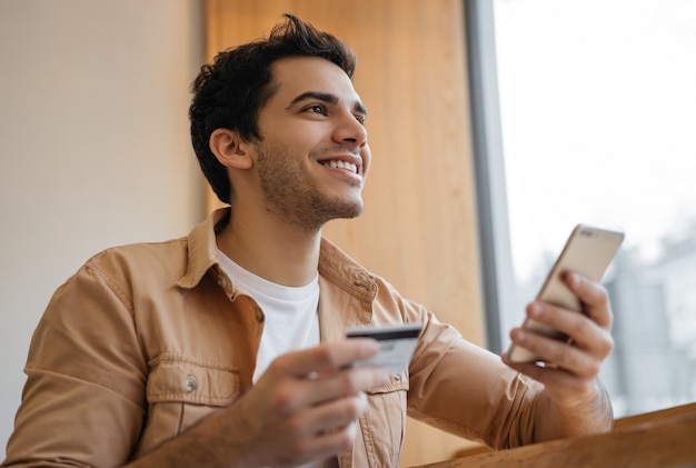 Indian man holding credit card and phone