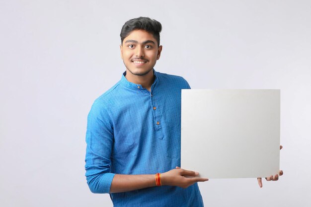 Indian man holding white board, promoting offers on festival season while wearing traditional cloths, standing over white background.