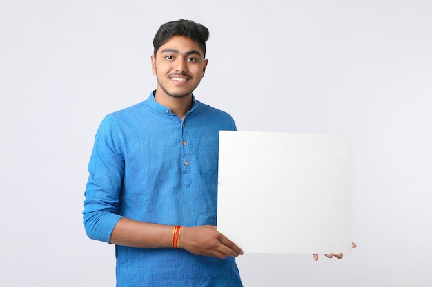 Indian man holding white board, promoting offers on festival season while wearing traditional cloths, standing over white background.