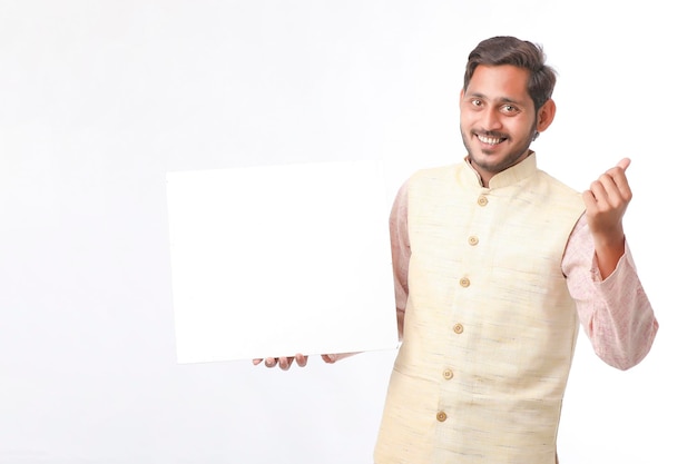 Indian man holding white board, promoting offers on festival season while wearing traditional cloths, standing over white background.