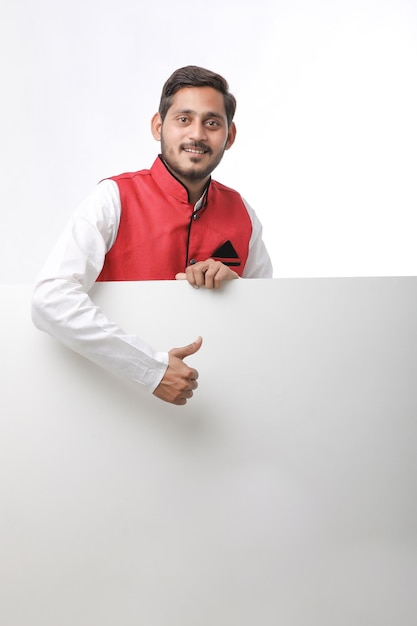 Indian man holding white board, promoting offers on festival season while wearing traditional cloths, standing over white background.