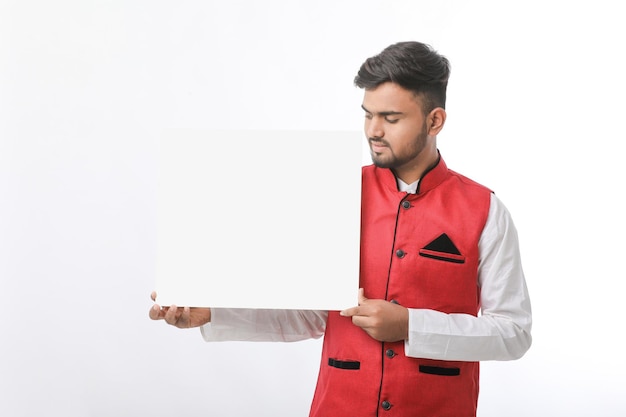 Indian man holding white board, promoting offers on festival season while wearing traditional cloths, standing over white background.