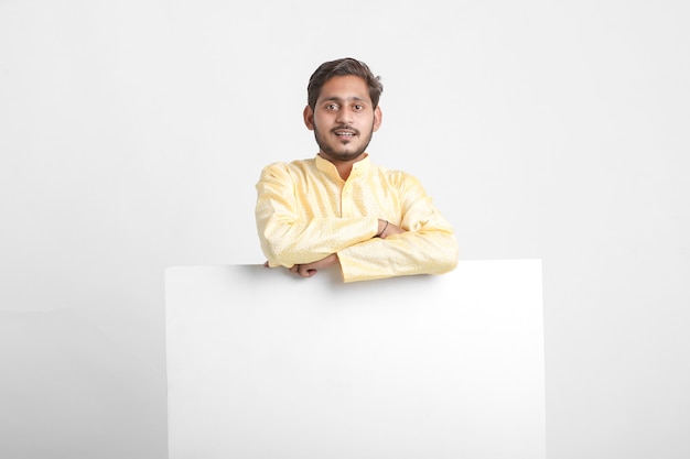 Indian man holding white board standing over white wall