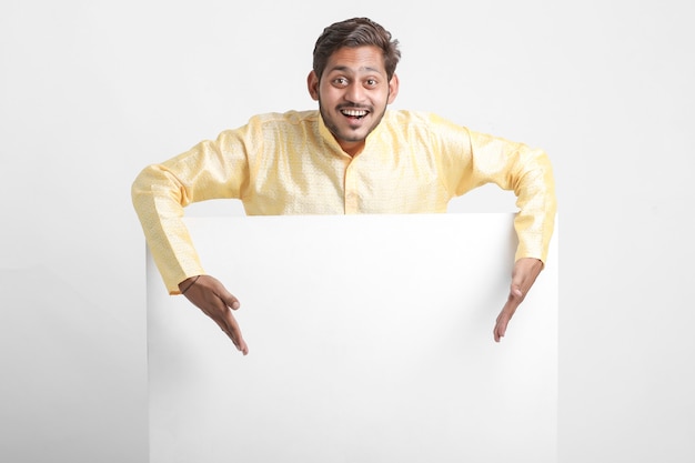 Индийский мужчина держит белую доску, стоящую над белой стеной