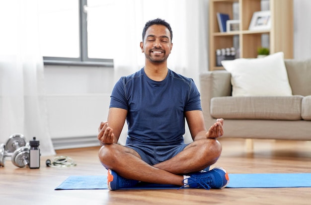 Photo indian man meditating in lotus pose at home