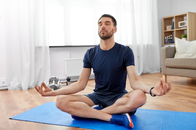 Photo indian man meditating in lotus pose at home