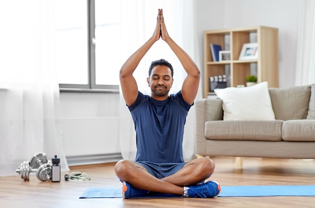 indian man meditating in lotus pose at home