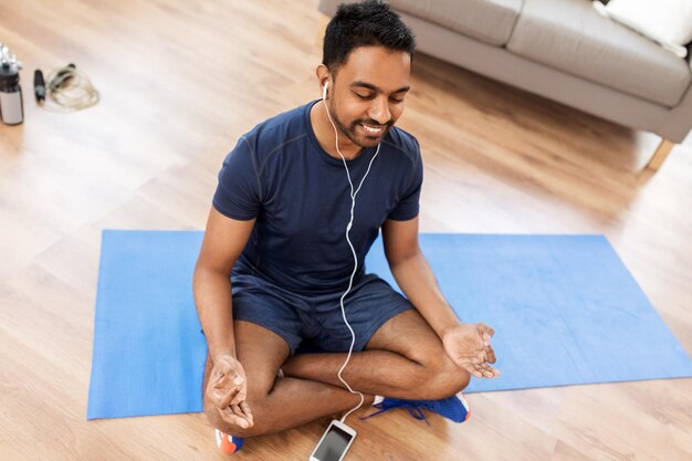 Photo indian man meditating in lotus pose at home