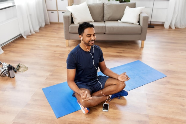 indian man meditating in lotus pose at home