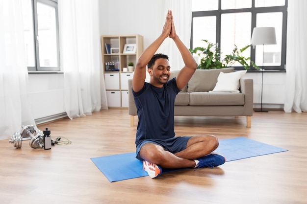 indian man meditating in lotus pose at home