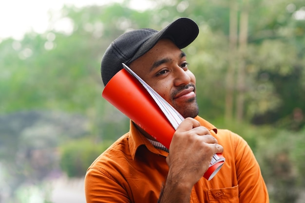 Indian man in orange shirt studying outside campus