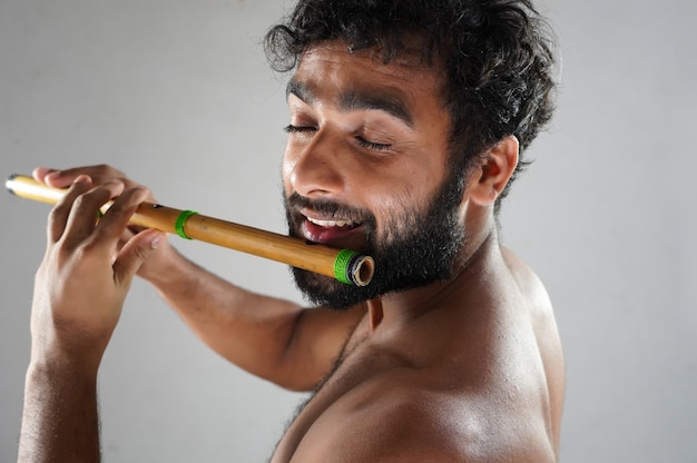 Indian man playing flute with passion