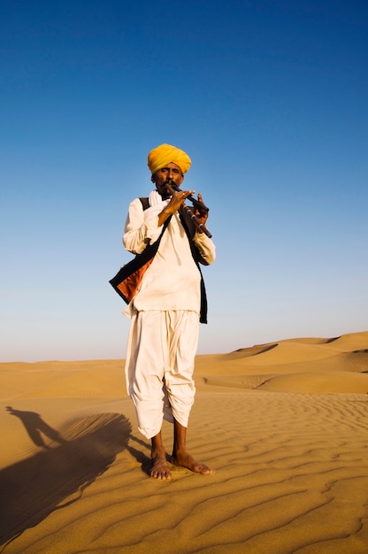 Индийский человек играет на ветру в пустыне