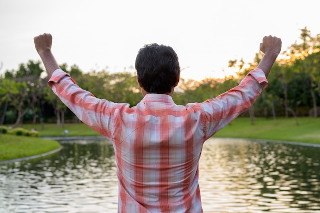 Indian man raising both his arms against scenic view