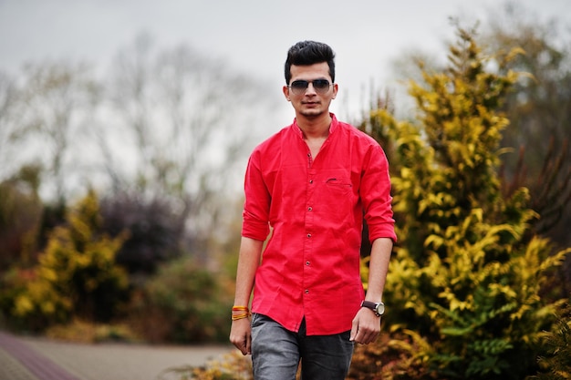 Indian man at red shirt and sunglasses posed outdoor