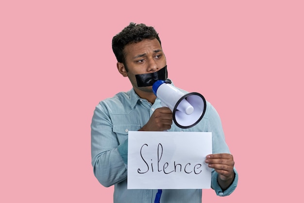 Indian man taped mouth speaks in megaphone censorship and free speech concept isolated on pink