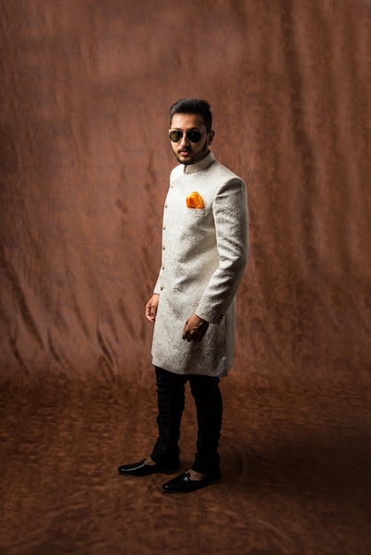 Photo indian man in traditional wear or kurta, pyjama cloths.  male fashion model in sherwani, posing or standing against brown grunge background, selective focus