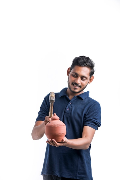 Indian man using hammer for broken clay piggy bank.