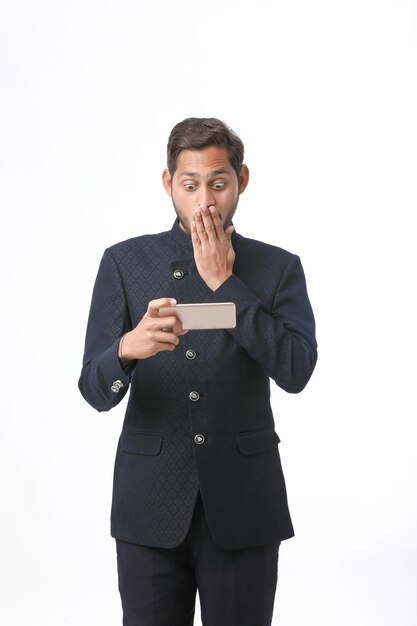 Indian man using smartphone on white background.