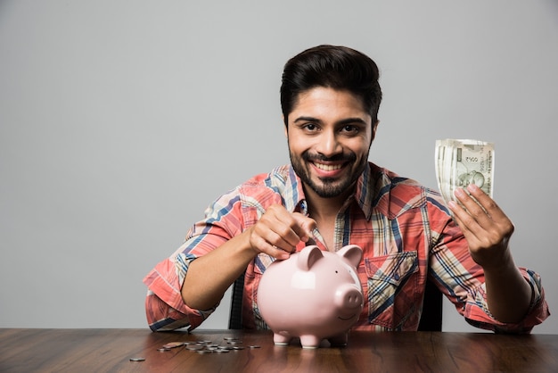 Indian Man with Piggy Bank, sitting at table