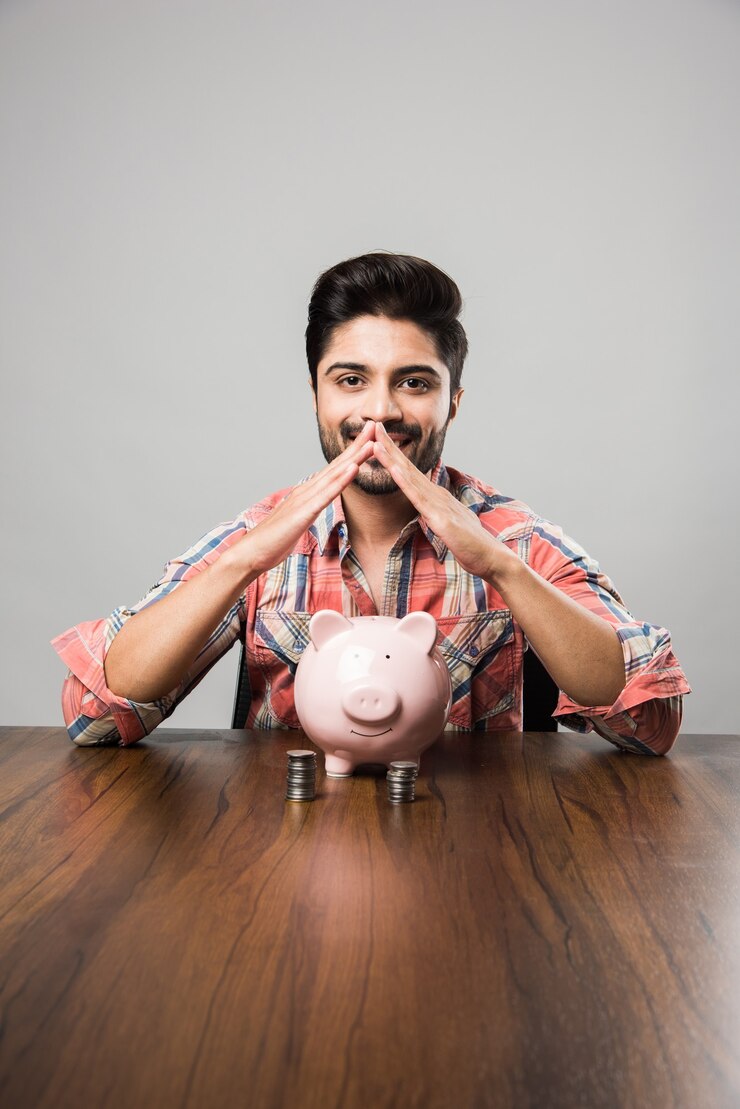 फोटो indian man with piggy bank, sitting at table