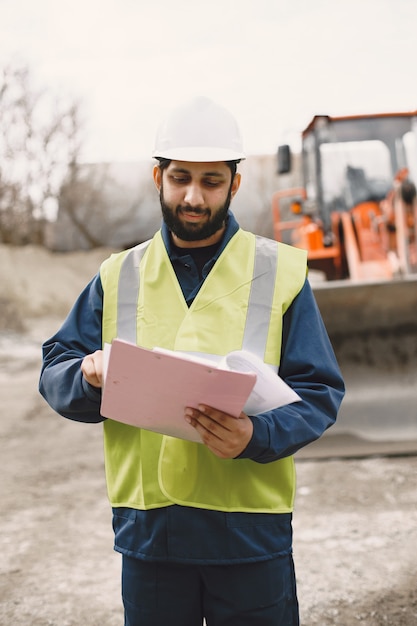 Indian man working. Male in a yellow vest. Man with folder.