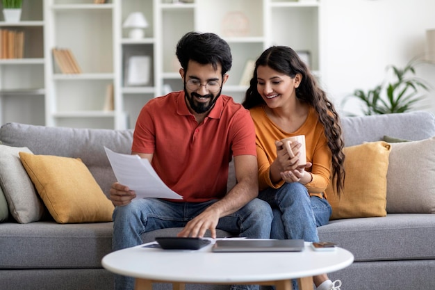 Indian married couple planning budget together reading papers and calculating spends