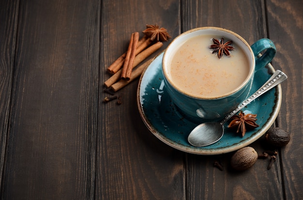 Indian masala chai tea. Spiced tea with milk on the dark wooden table.