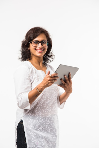 Indian mid age lady or women using tablet pc while standing isolated over white background, selective focus