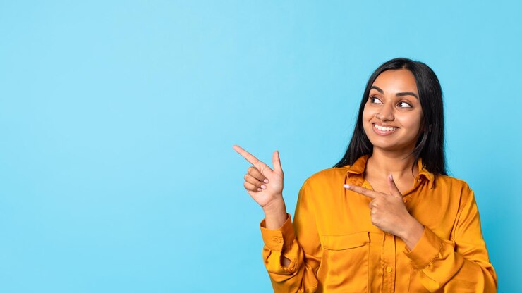 फोटो indian millennial woman in casual excitedly pointing aside blue background