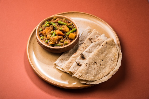 ジャガイモと豆を含むインドの混合野菜と伝統的なマサラとカレーをチャパティまたはロティまたはインドのフラットブレッドと一緒に提供