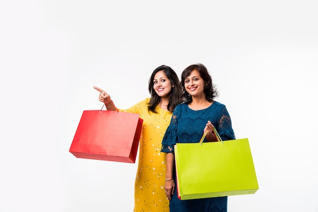 Indian Mother daughter sisters shopping with colourful bags, standing isolated over white background