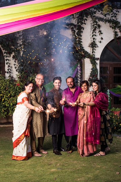 Indian multigenerational family celebrating Diwali festival by playing with firecrackers outside home