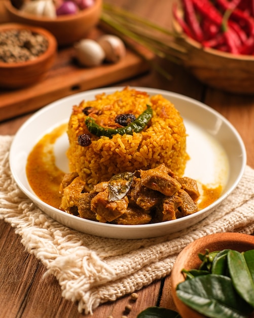 인도 양고기 Biryani 요리는 나무 테이블에 제공됩니다. 향신료와 바스마티 쌀을 섞은 염소 고기로 만든 인도의 전형적인 음식