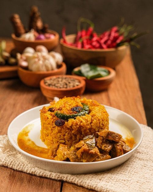 Indian Mutton Biryani Dish served on wooden table. Typical food from India, made from goat meat mixed with spices and basmati rice