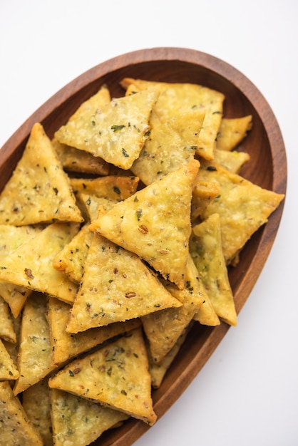 Photo indian namkeen palak or methi mathri triangle shape or tikona - salted fenugreek or spinach leaves mixed crackers