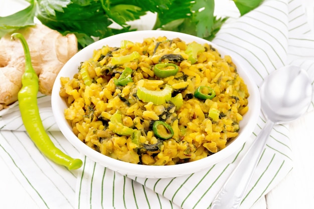 indian national dish of kichari made of mung bean, rice, stalk celery, spinach, hot pepper in bowl